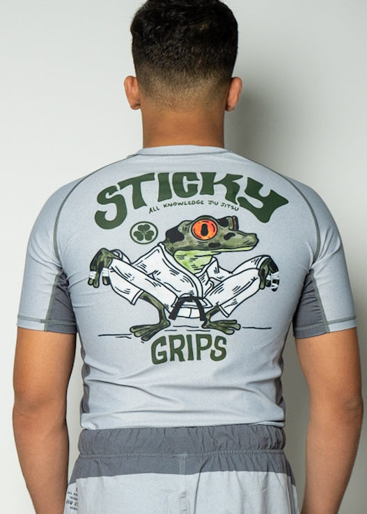 Person wearing a gray rashguard with 'Sticky Grips' graphics on the back.