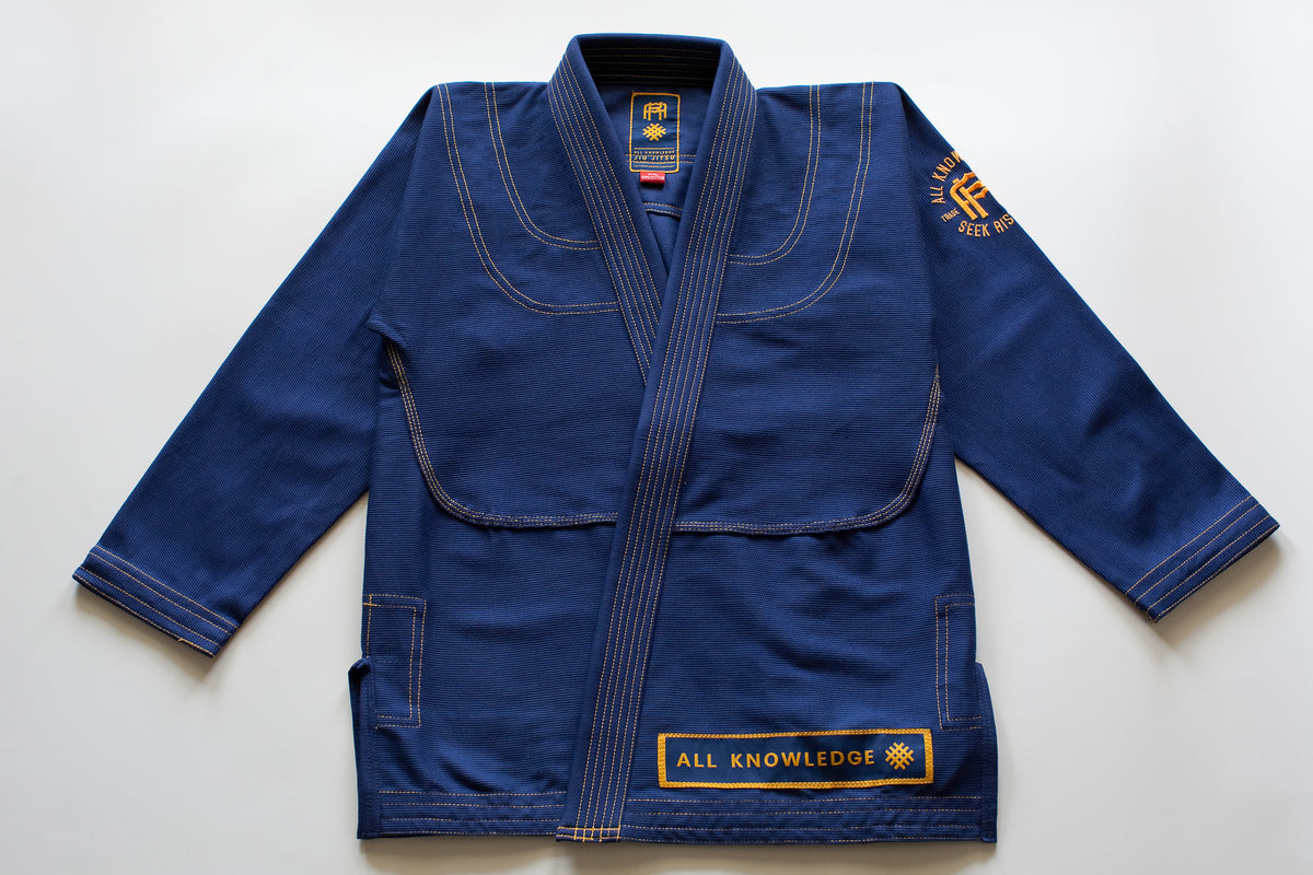 All Knowledge blue Brazilian Jiu-Jitsu Gi with gold stitching, embroidered AK logos, Seek Risk Live sleeve design, matching pants, and branded patches, displayed flat on a white background.