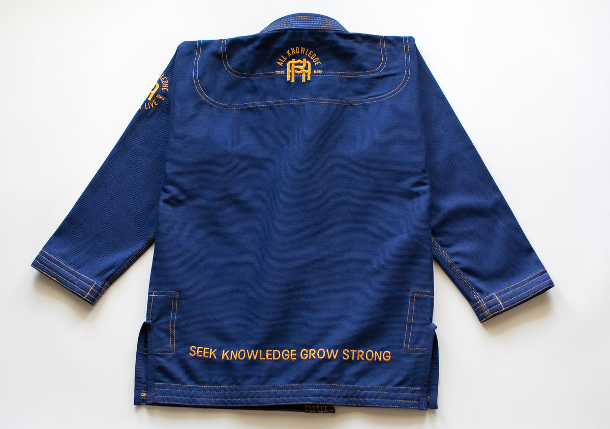 All Knowledge blue Brazilian Jiu-Jitsu Gi with gold stitching, embroidered AK logos, Seek Risk Live sleeve design, matching pants, and branded patches, displayed flat on a white background.