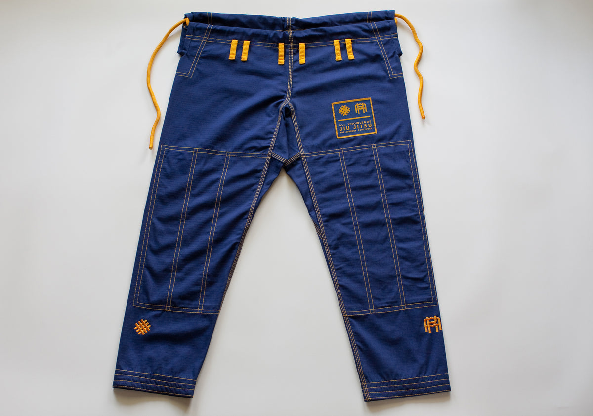All Knowledge blue Brazilian Jiu-Jitsu Gi with gold stitching, embroidered AK logos, Seek Risk Live sleeve design, matching pants, and branded patches, displayed flat on a white background.