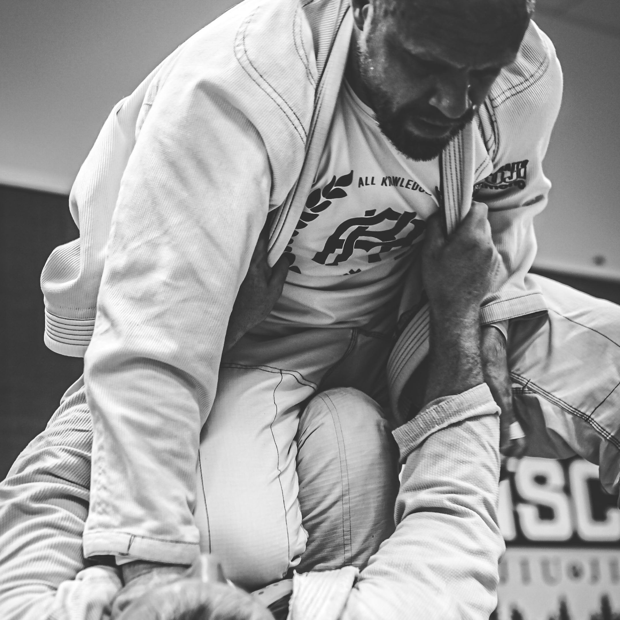 Two individuals wearing all knowledge  in a martial arts or grappling position on a mat.